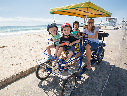 Family riding surrey bike on the beach path by the Bahia Resort Hotel in San Diego