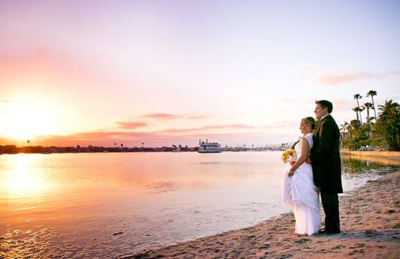 Wedding couple embracing on beach looking into the sunset