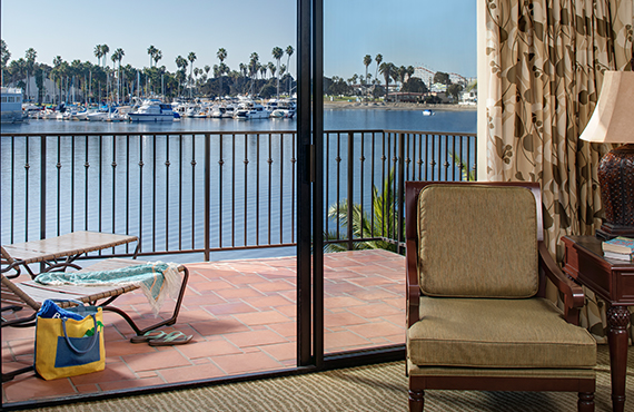 A junior suite with a balcony overlooking the water and palm trees.