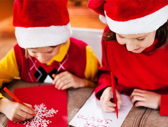 Young children writing letters to Santa at Mission Bay San Diego’s Bahia Resort Hotel Santa’s Letter Station on their San Diego Winter Vacation
