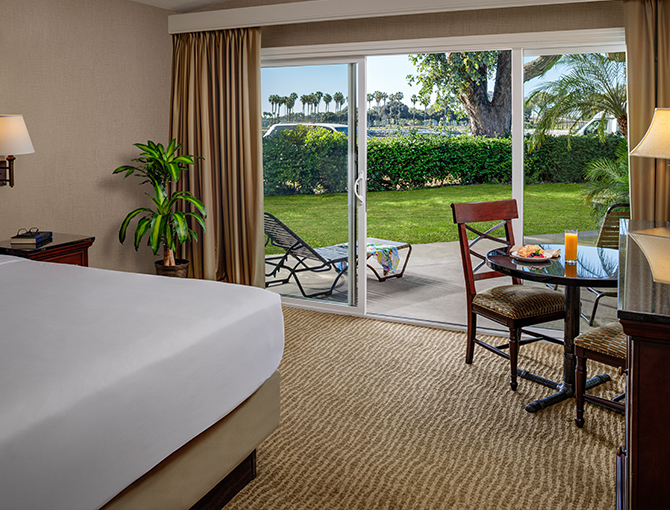 Resort View room with sliding doors opening to a patio with lush greenery at the Bahia Resort Hotel in Mission Beach, San Diego
