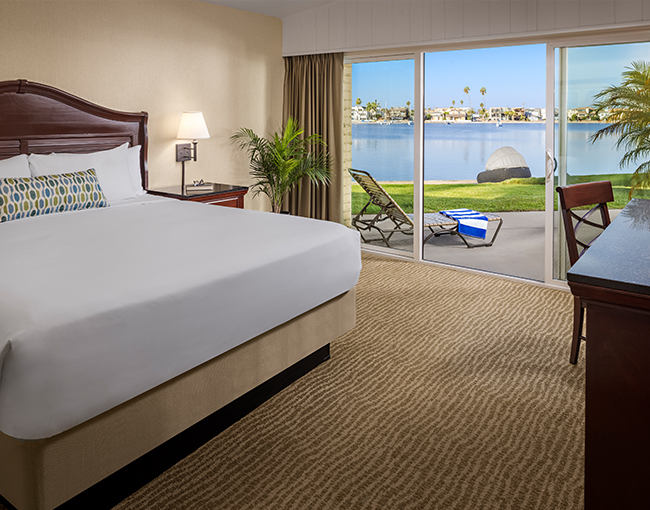  Queen bed and view of the patio and Mission Bay from a Bayfront Room at the Bahia Resort Hotel in Mission Beach, San Diego