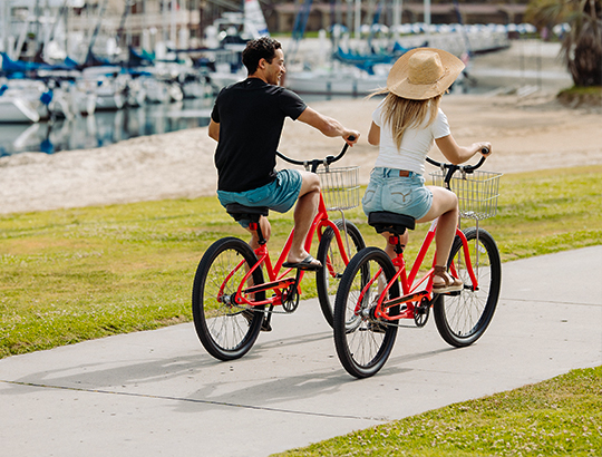 Couple riding bikes on the beach path by the Bahia Resort Hotel in San Diego