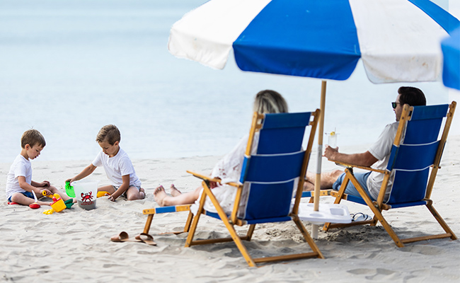 Family of four relaxing on the beach and playing in the sand on the private beach at the Bahia Resort Hotel on day 2 of their 3-day fall itinerary in San Diego.