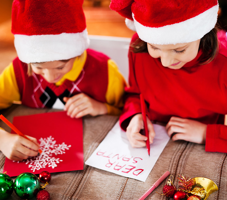 Young children writing letters to Santa at Mission Bay San Diego’s Bahia Resort Hotel Santa’s Letter Station on their San Diego Winter Vacation