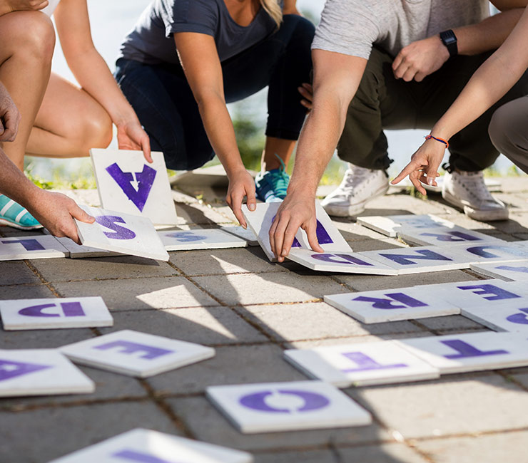 Adults working together in a team building event to solve a life size crossword puzzle at the Bahia Resort Hotel in San Diego.