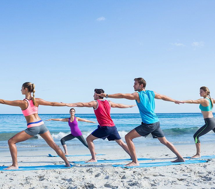 Co-workers experiencing yoga on the beach in Mission Bay, one of the many team building events at the Bahia Resort Hotel in San Diego.