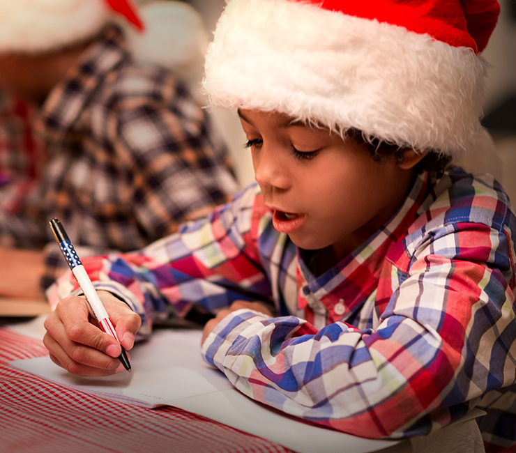 Young child writing a letter to Santa at Mission Bay San Diego’s Bahia Resort Hotel Santa’s Letter Station on their San Diego Winter Vacation