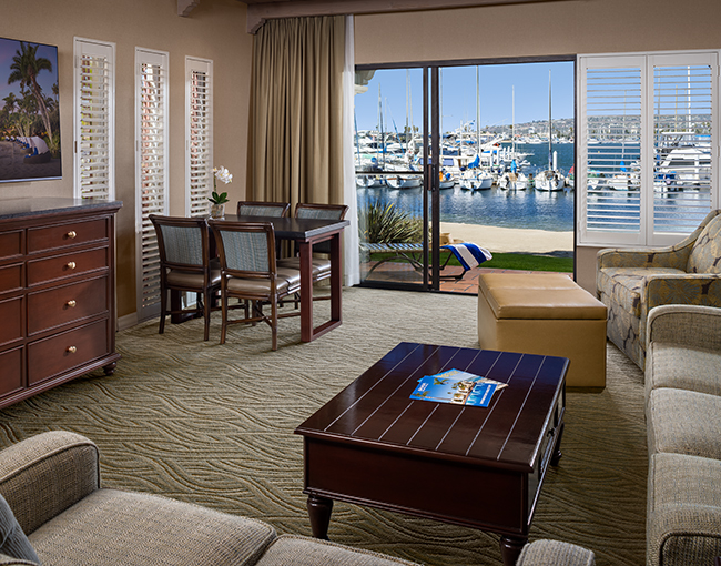 Marina Suite living room area with dining table, couches and a tv at the Bahia Resort Hotel in Mission Beach, San Diego
