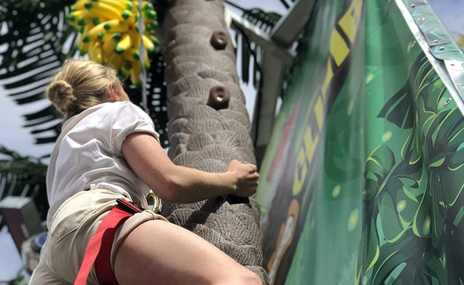 Girl climbing coconut tree at Coconut Climb Ride at Belmont Park