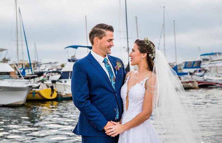Bride and groom gazing into each others eyes with boats as their backdrop at the Bahia Resort Hotel