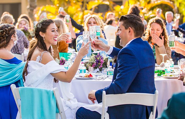 A bride and groom are toasting with champagne glasses at a wedding reception.