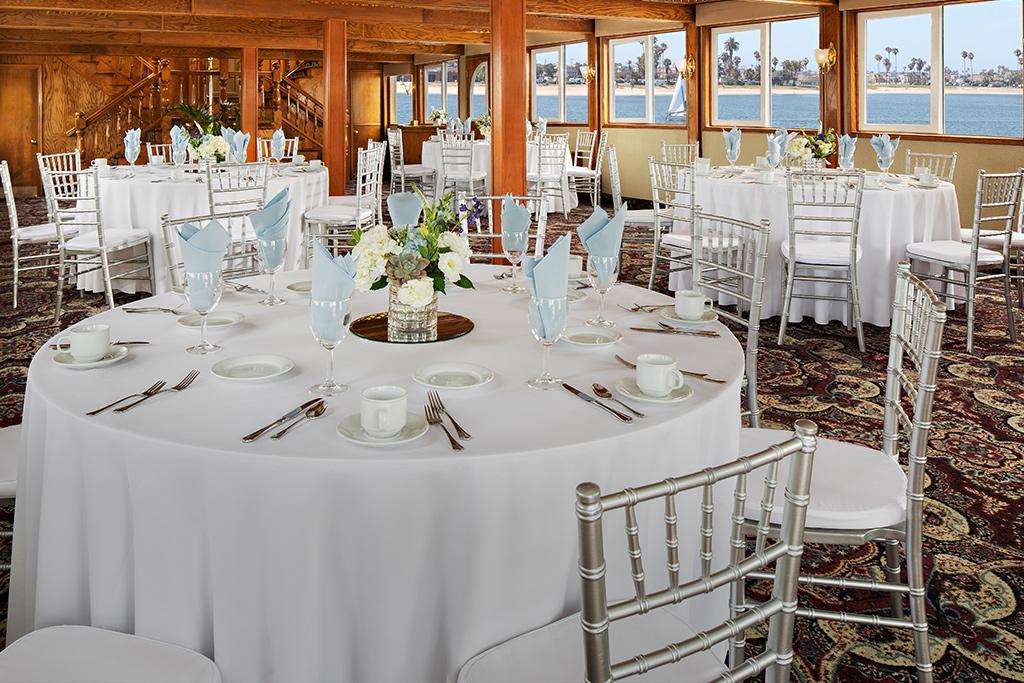 White and silver table arrangements for a special occasion on the Bahia Belle private event boat in San Diego, CA
