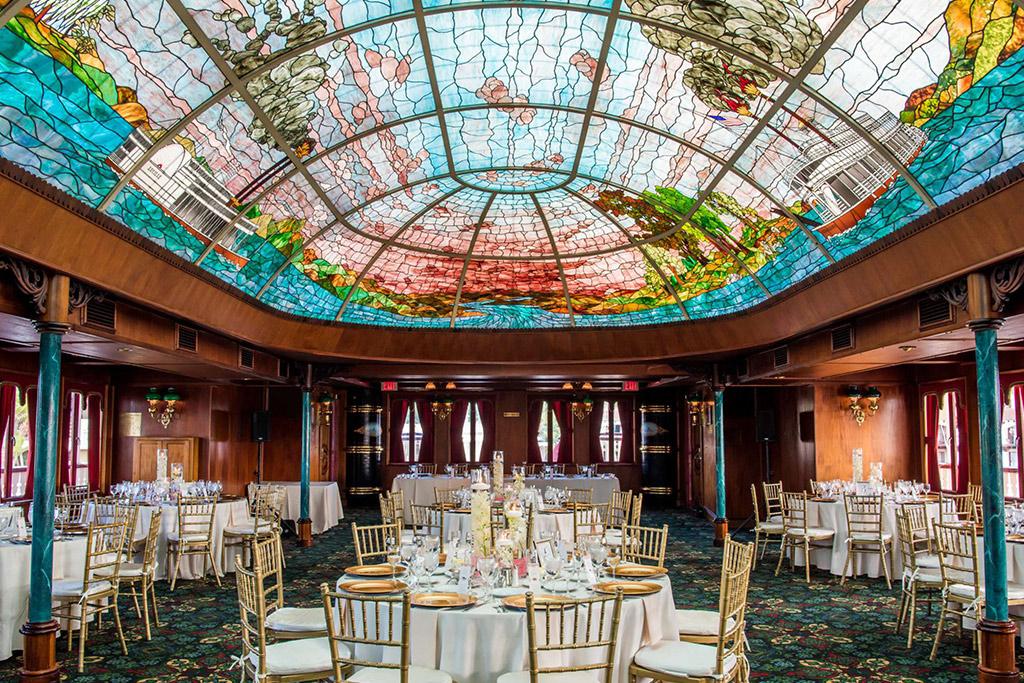 The interior of the William D Evans with its stunning stained-glass ceiling and white and gold table arrangements.