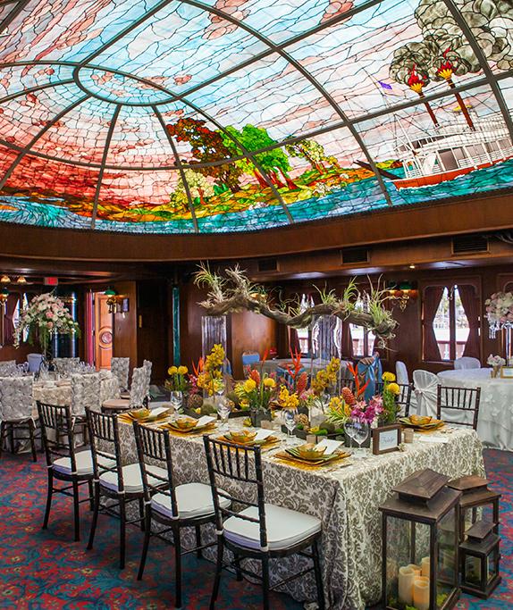 The William D Evans Sternwheeler with a majestic stained-glass ceiling is set up for a celebration in a private event boat rental in San Diego.